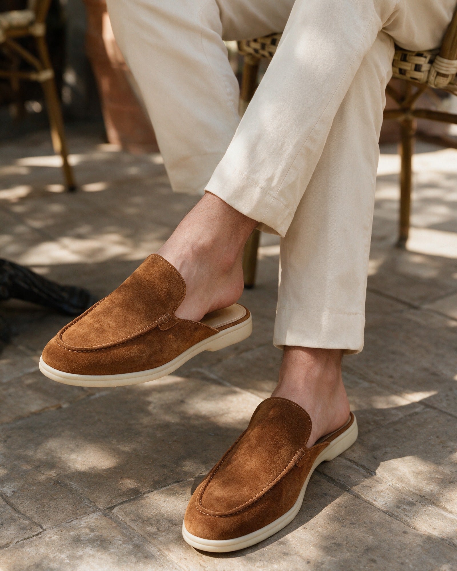 Cognac suede slippers worn seated outside a cafe