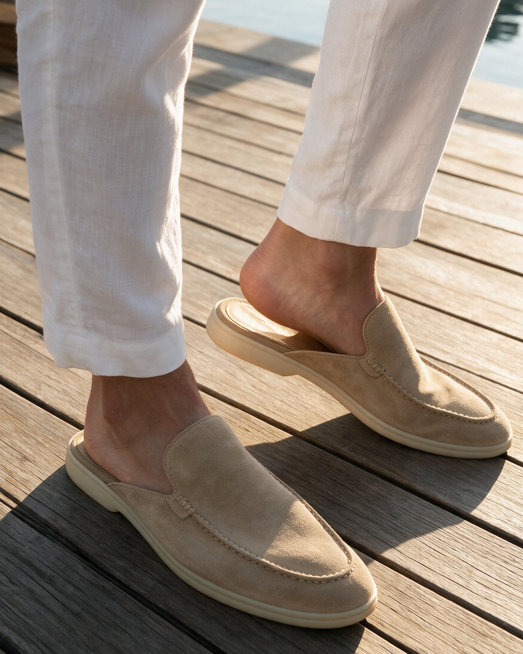Beige suede slippers worn on a teak deck