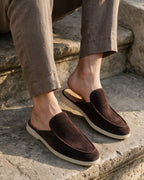 Dark brown suede slippers worn on a stone step