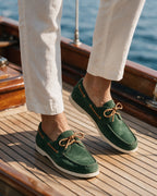 Lorvano Foil Suede Boat Shoes in green suede with rawhide lacing worn on a teak yacht deck
